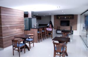 a kitchen with wooden tables and chairs and a woman at Rapport Hotel in Juazeiro