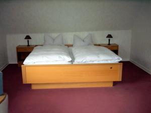 a wooden bed with white sheets and pillows on it at Gasthof Haus Hubertus in Winterberg