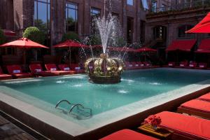a fountain in a pool with red chairs and umbrellas at Faena Hotel Buenos Aires in Buenos Aires