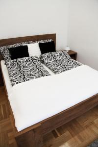 a white bed with black and white sheets and pillows at Brand New Apartment Budapest in Budapest