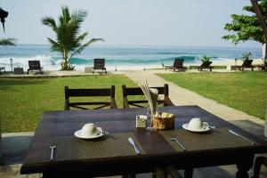 a wooden table with hats and napkins on the beach at Amanda Beach Villas in Unawatuna