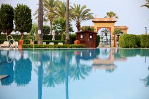a swimming pool with a house and palm trees at Iberostar Waves Málaga Playa in Torrox Costa