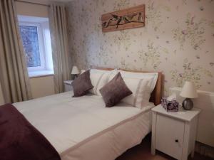 a bedroom with a white bed with flowers on the wall at Cardinals Folly in Kinghorn