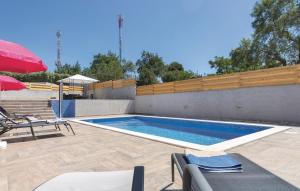 a swimming pool with chairs and a red umbrella at Apartments Klaudija in Pula
