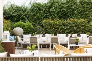 a patio with white chairs and tables and bushes at Palacio de los Duques Gran Meliá - The Leading Hotels of the World in Madrid