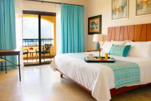 Un dormitorio con una cama con una bandeja de comida. en Las Villas Hotel & Golf By Estrella del Mar, en Mazatlán
