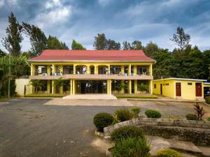 une grande maison jaune avec un toit rouge dans l'établissement Mvuli Hotels Arusha, à Arusha