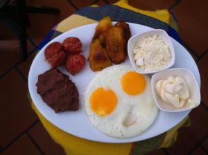 a plate of breakfast food with eggs meat and other foods at Plaza Yat B'alam in Copán Ruinas