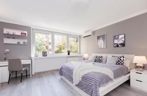 a white bedroom with a bed and a desk at Warsawrent Hit Apartments in Warsaw