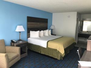 a hotel room with a bed and a chair at Baymont by Wyndham Anderson Clemson in Anderson