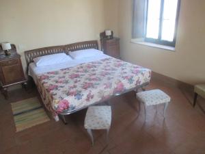 a bedroom with a bed with a floral bedspread and two chairs at Agriturismo Stigliano in Sarteano