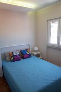 a bedroom with a blue bed with pillows and a window at Lisbon Beach Apartments 4 in Costa da Caparica