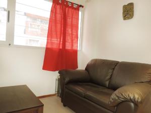 sala de estar con sofá marrón y ventana en Departamento Maipú en Rosario