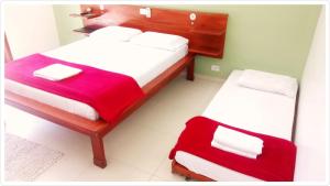 a bedroom with two beds with red and white sheets at Pousada Filhos da Terra in Trindade