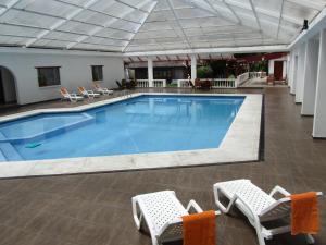 伊瓦拉的住宿－La Quinta San Andrés，一座带椅子的大型游泳池和一座建筑