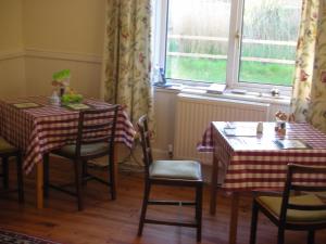 a dining room with two tables and chairs and a window at The Cockatrice B&B in Reedham