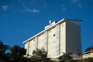 un edificio de hotel con un cielo azul en el fondo en AJ Hotel Chapecó - Fácil Acesso Pátio Shopping e Rótula da Bandeira, en Chapecó