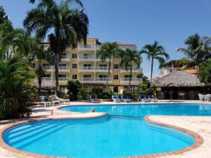 a swimming pool with a resort in the background at Las Palmeras RIKI R in Boca Chica