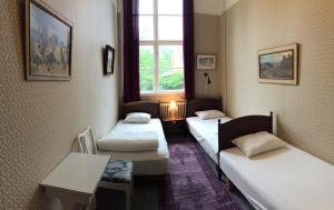 Cette chambre comprend 3 lits, une table et une fenêtre. dans l'établissement Tivedens Hostel-Vandrarhem, à Karlsborg