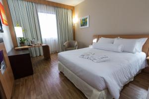 una habitación de hotel con una cama grande con sábanas blancas en Novotel Porto Alegre Tres Figueiras en Porto Alegre