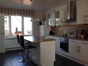 a kitchen with white cabinets and a counter with chairs at Vier Sterne am Hafen, Ditzum in Ditzum