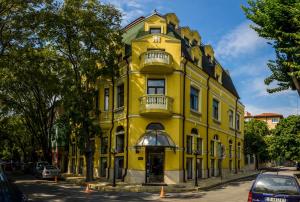 un edificio amarillo con un reloj encima en Hi Boutique Hotel, en Varna