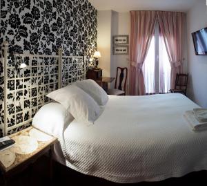 1 dormitorio con cama blanca y papel pintado en blanco y negro en Ch Hostal Victoria, en Cuenca