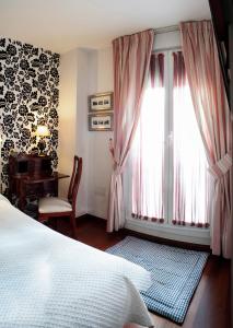 a bedroom with a bed and a desk and a window at Ch Hostal Victoria in Cuenca