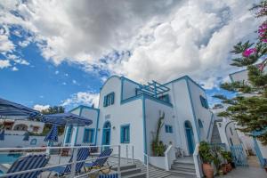 a group of white buildings with chairs and umbrellas at Preka Maria in Kamari