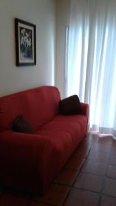 - un canapé rouge dans le salon avec des rideaux dans l'établissement COMFORT GUARUJÁ ENSEADA APARTMENT 26 WIFI, GARAGEM e AR CONDICIONADO, à Guarujá