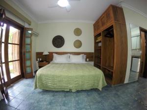 a bedroom with a large bed with a green bedspread at Ilha Flat Hotel-Ilhabela apart Schiavettii in Ilhabela