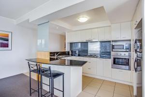 a kitchen with white cabinets and a black counter top at Mantra Broadbeach on the Park in Gold Coast