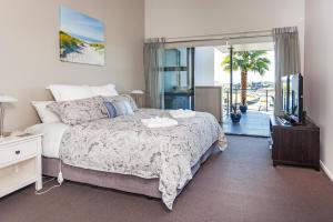 a bedroom with a bed and a television and a balcony at Sovereign Pier On The Waterways in Whitianga