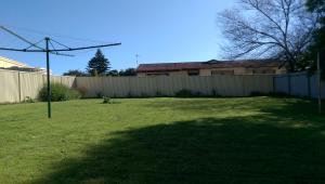 a yard with a fence and a large grassy field at My Port Lincoln Place in Port Lincoln