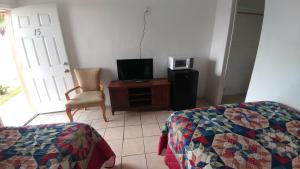 Schlafzimmer mit einem Bett, einem TV und einem Stuhl in der Unterkunft Anchor Motel & RV Park in Surfside Beach