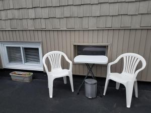 two white chairs and a table next to a house at Green Dolphin Motel in Old Orchard Beach