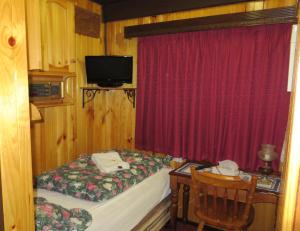 Karelia Alpine Lodge في فولز كريك: غرفة صغيرة بها سرير وتلفزيون وطاولة