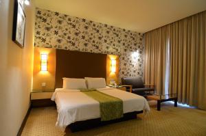 a hotel room with a large bed and a chair at Eastwood Valley Golf & Country Club in Miri +42 photos