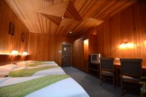 Habitación con 3 camas, escritorio y TV. en Eastwood Valley Golf & Country Club en Miri