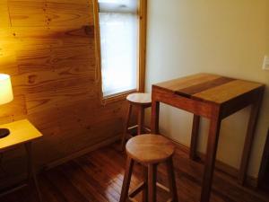Zimmer mit zwei Hockern, einem Tisch und einem Fenster in der Unterkunft Canquen Patagonia in Punta Arenas