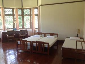 una stanza con due letti, un tavolo e finestre di Morris Bungalow a Passara