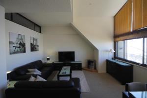 a living room with a couch and a tv at Arlberg Hotham in Mount Hotham