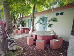 a patio with pink tables and stools and trees at Hotel y Restaurante Rincón Familiar in La Libertad