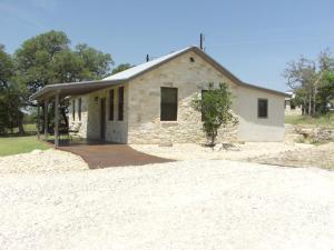 a small stone house on the side of a dirt road at Breezy Hills Cottages - Morning Sun Cottage in Fredericksburg