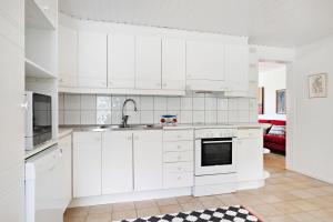 uma cozinha com armários brancos e um lavatório em Charming townhouse em Ystad