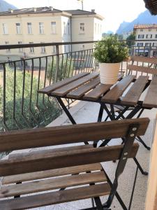 een houten picknicktafel op een balkon met een potplant bij Creative Apartment in Dro
