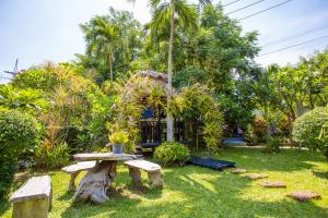 einen Garten mit einer Bank und einem Baumstumpf in der Unterkunft First Pacific Hotel and Convention in Pattaya