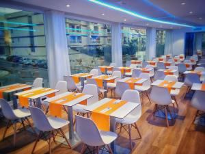 a room with tables and white chairs and windows at MB Boutique Hotel - Adults Recommended in Nerja