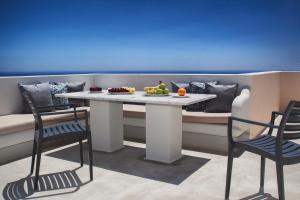 a table with a bowl of fruit and two chairs at Santa Rinoula Suites Ocean Caldera Sunset Views in Megalochori