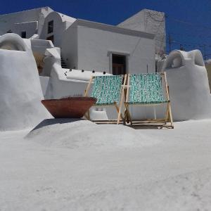 two chairs in the sand in front of a house at Olyra Traditional Cave Houses in Pirgos
